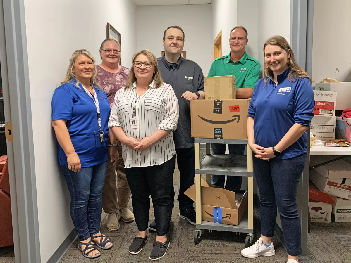 Representatives from ILCAO's One-Stop Center, United Way of the River Cities, and Amazon unpack donations for the One-Stop Donation Closet.